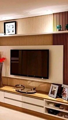 a flat screen tv sitting on top of a wooden entertainment center next to a vase with red flowers