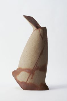 a white and brown vase sitting on top of a table next to a black object