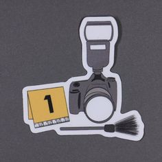 a camera with a yellow sticker on it next to a brush and a card