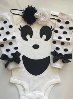 a white bodysuit with black and white polka dots on the front, featuring an image of a smiling face