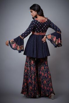 Navy blue tie-up top with floral embroidery and bell sleeves. Paired with printed, embroidered palazzo and blouse.
Component: 3
Pattern: Printed,Embroidered
Type Of Work: Floral
Neckline: Blouse: V neck
Sleeve Type: Top: Bell Sleeves
Fabric: Rayon Crepe
Color: Blue
Other Details: 
Tie-up top
Printed palazzo
Occasion: Sangeet - Aza Fashions Bohemian Blue Palazzo Set With Printed Motifs, Festivals Long Sleeve Palazzo Set With Floral Embroidery, Long Sleeve Floral Embroidery Palazzo Set For Festivals, Festival Long Sleeve Palazzo Set With Floral Embroidery, Festival Floral Embroidered Long Sleeve Palazzo Set, Blue Embroidered Bohemian Palazzo Set, Bohemian Blue Set With Floral Embroidery, Bohemian Blue Sets With Floral Embroidery, Blue Bohemian Sharara With Floral Print