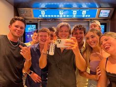 a group of people taking a selfie in front of a tv screen with their cell phones