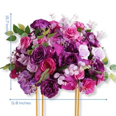 a bouquet of purple and pink flowers sitting on top of two gold sticks with measurements