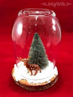 a snow globe with a small christmas tree in it and a deer figurine