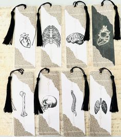 six bookmarks with drawings on them and tassels hanging from the pages in front of them