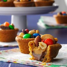 two cupcakes with candy and candies in them sitting on a table next to a cake plate