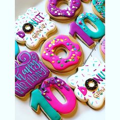 there are many decorated donuts on the table with happy birthday written on them in pink, blue and green