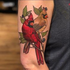 a couple of birds sitting on top of a tree branch with leaves around their necks