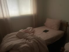 an unmade bed sitting next to a window in a bedroom