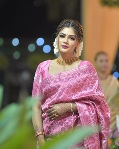 a woman in a pink sari and gold jewelry