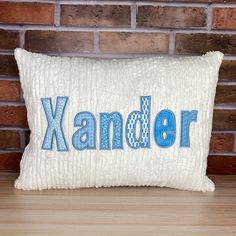 a white pillow with the word xanander on it sitting next to a brick wall