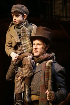 a man holding a young boy on his shoulders in a scene from the play les miserables