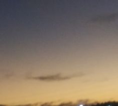 an airplane is flying in the sky at night with some clouds and lights behind it