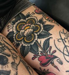 a woman's legs with tattoos on them and flowers in the middle of her leg