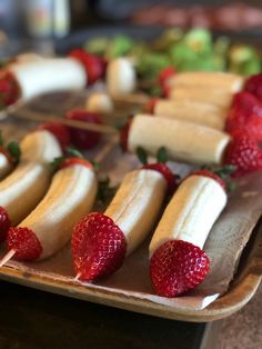 some bananas and strawberries are arranged on a tray with toothpicks in them