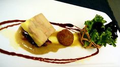 a white plate topped with food and garnish on top of a wooden table