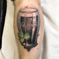 a man's leg with a guinness tattoo on it and shamrocks around the legs