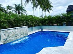 an empty swimming pool surrounded by palm trees and water features a stone wall that wraps around it