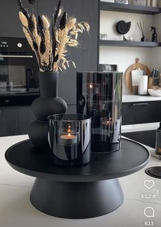 a black table with two vases filled with flowers and candles sitting on top of it