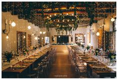 a long table is set up in the middle of a room with lights hanging from the ceiling