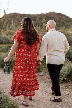 a man and woman walking down a dirt road