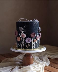 a black and gold decorated cake sitting on top of a wooden table