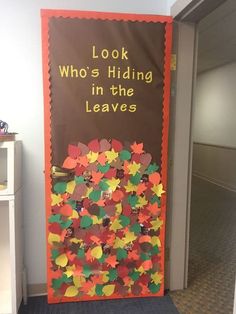 a door decorated with paper leaves and the words look who's hiding in the leaves