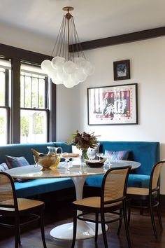 a dining room table with chairs and a blue couch in front of a large window