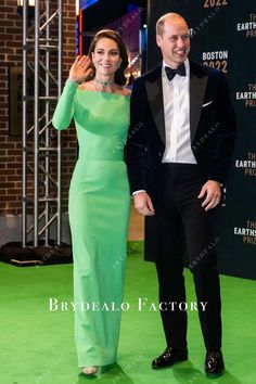 a man and woman in formal wear walking down the green carpet