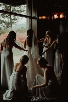 a group of women standing next to each other in front of a window