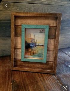 a painting in a wooden frame on top of a wood floor next to a wall