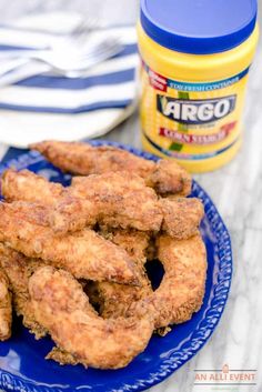 fried onion rings on a blue plate next to a jar of argo powdered sugar