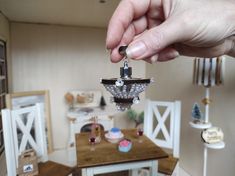 a person is holding up a miniature model of a house with cupcakes on the table