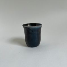 a black cup sitting on top of a white table