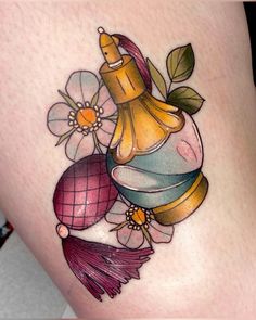 a tattoo with flowers and perfume bottles on the side of a woman's thigh