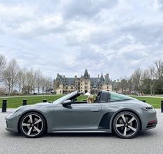 a grey sports car parked in front of a castle