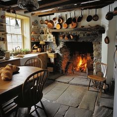 an old fashioned kitchen with a fire in the fireplace and pots hanging from the ceiling