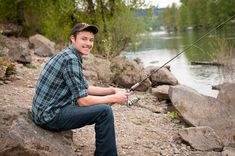 a man sitting on rocks with a fishing rod