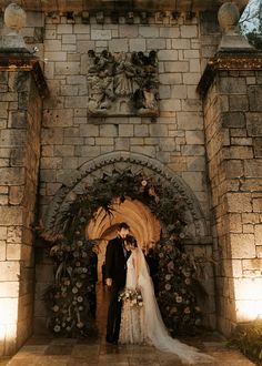 a bride and groom standing in front of an archway