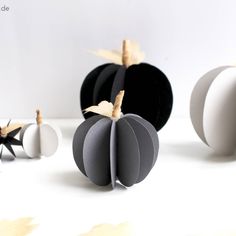 three black and white paper pumpkins on a table with one cut out to look like an apple