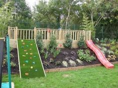 a backyard play area with a slide, grass and flowerbeds in the background