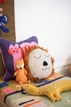 a stuffed animal is sitting on a bed next to a pillow and other toys in the room