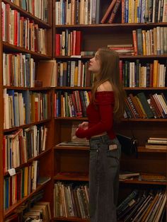 a woman standing in front of a book shelf filled with books