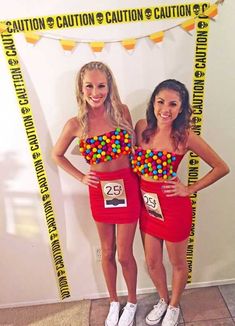 two women standing next to each other in front of a sign that says gumball machines