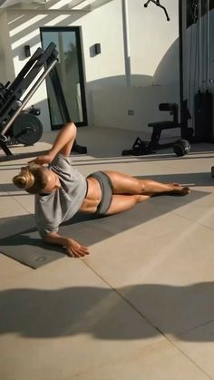 a woman laying on the ground in front of a gym equipment line with her legs spread out