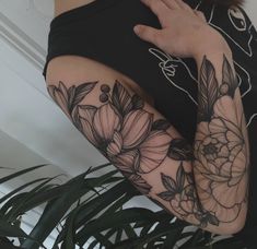 a woman's arm with flowers and leaves on it