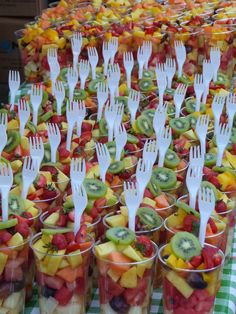 there are many plastic forks in cups filled with fruit