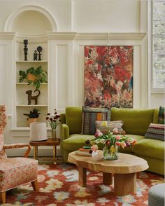 a living room with green couches and colorful rugs in front of a painting on the wall