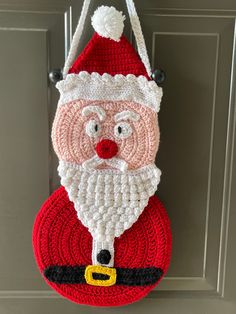 a crocheted santa clause bag hanging on a door hanger in front of a door