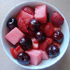 a white bowl filled with watermelon, blueberries and strawberries on top of a table